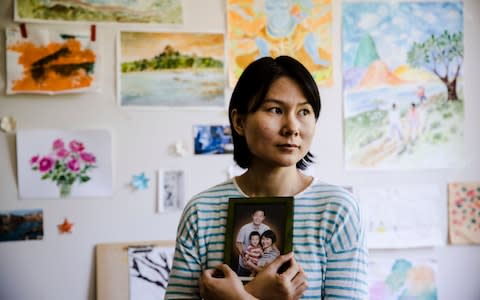 n this Wednesday, May 9, 2018 file photo, Hua Qu, the wife of detained Chinese-American Xiyue Wang, poses for a photograph with a portrait of her family in Princeton, N.J - Credit: AP