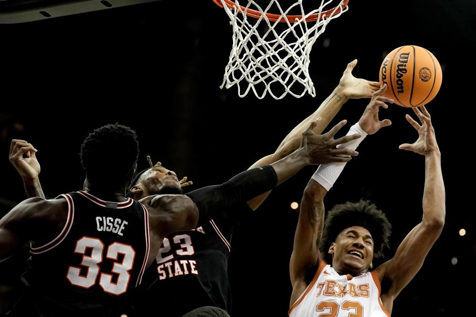 Texas forward Dillon Mitchell, right, battles Oklahoma State forwards Moussa Cisse (33) and Tyreek Smith (23) for a rebound during the first half of an NCAA college basketball game in the second round of the Big 12 Conference tournament Thursday, March 9, 2023, in Kansas City, Mo. (AP Photo/Charlie Riedel)