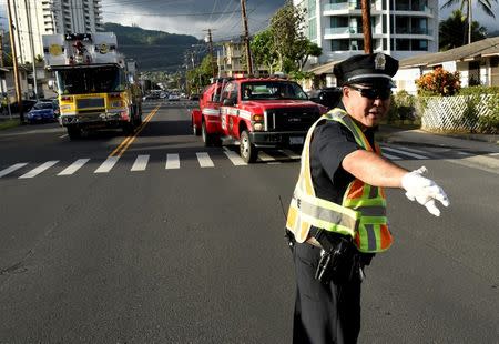 A police officer directs a fire truck to the Marco Polo apartment building after a fire broke out in it in Honolulu, Hawaii, July 14, 2017. REUTERS/Hugh Gentry