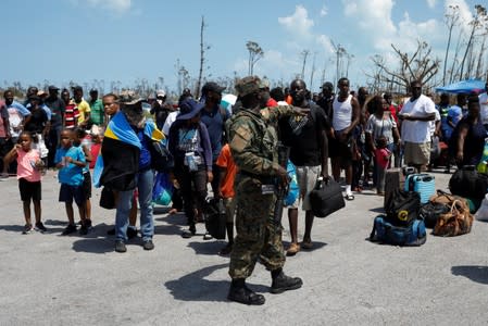 A soldier controls the crowd as people wait in line to get in a airplane during an evacuation operation after Hurricane Dorian hit the Abaco Islands in Treasure Cay