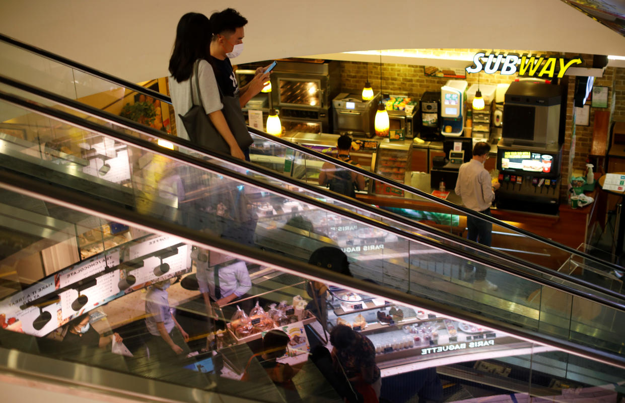 People wearing protective face masks ride an escalator at a shopping mall, amid the coronavirus disease (COVID-19) outbreak, in Singapore July 14, 2020. REUTERS/Edgar Su