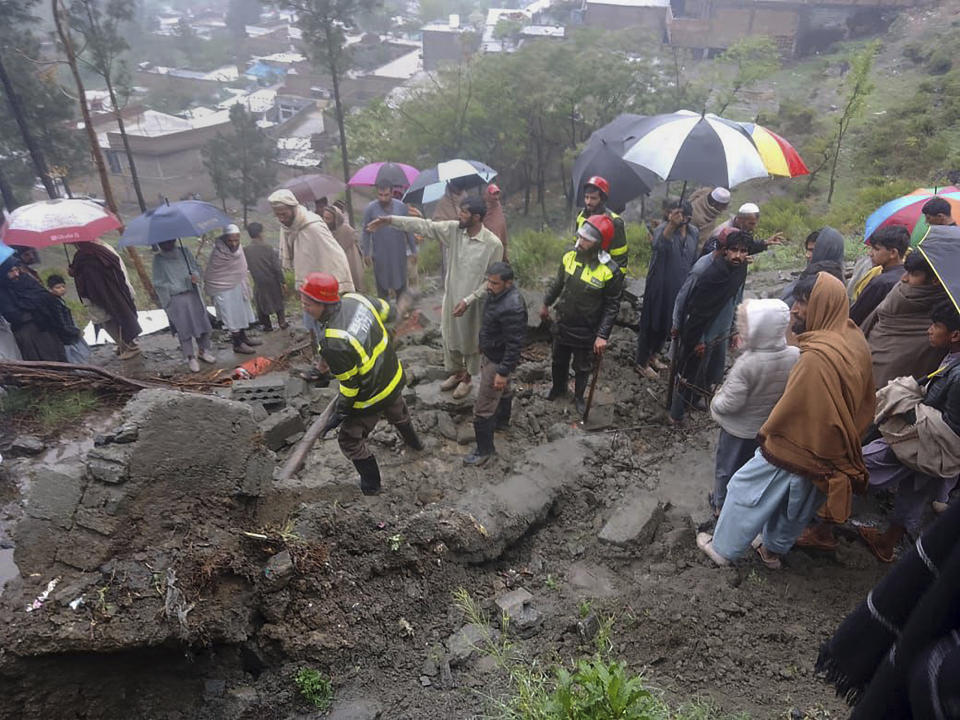 In this photo provided by the Rescue 1122 Emergency Department, rescue workers and locals gather to clear the rubble of a house partially damaged by landslide due to heavy rainfall in Matta, a town in Swat Valley, Pakistan, Sunday, April 14, 2024. Lightening and heavy rains killed dozens of people, mostly farmers, across Pakistan in the past three days, officials said Monday, as authorities declared a state of emergency in the country's southwest following an overnight rainfall to avoid any further casualties and damages. (Rescue 1122 Emergency Department via AP)