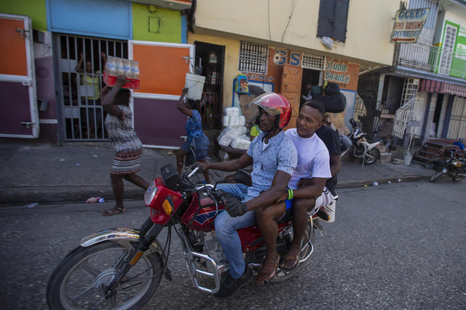 A motorcycle taxi transports Jhon Celestin, deported from the United States two days earlier, to go buy sneakers in Port-au-Prince, Haiti, Friday, Sept. 24, 2021. Before leaving Haiti again, Celestin is planning a trip to the coastal city of Jacmel in southern Haiti to see more relatives, a risky trip because it entails crossing gang-controlled territory. (AP Photo/Joseph Odelyn)