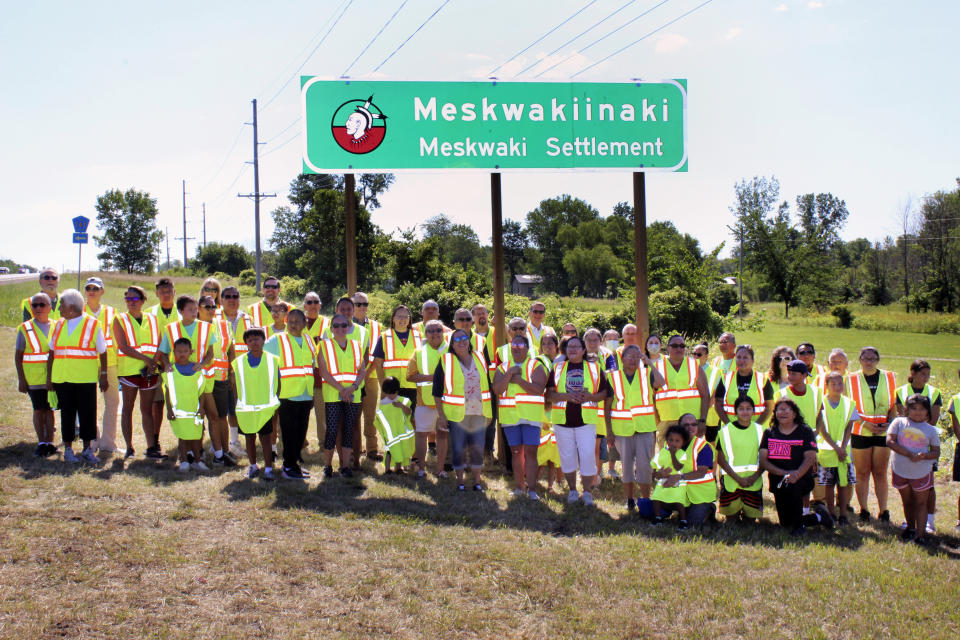 This photo taken July 13, 2022 provided by the Iowa Department of Transportation, members of the Meskwaki Nation along with employees from the Iowa Department of Transportation and Federal Highway Administration stand in front of a sign on US Highway 30 that features the Meskwaki Nation's own spelling of the tribe, Meskwakiinaki. (Iowa Department of Transportation via AP)