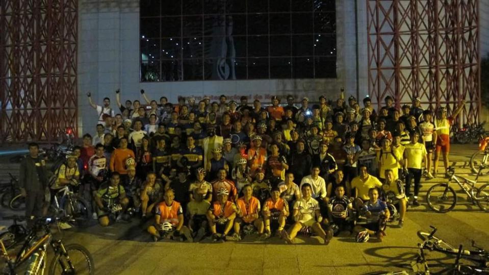 a large group of cyclists take a group photo