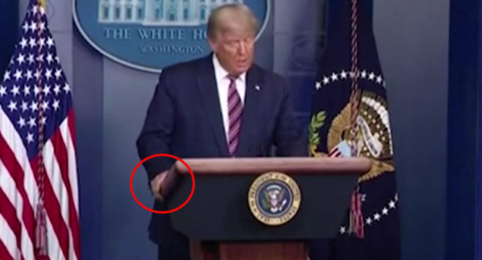 A red circle is around Donald Trump's hand to indicate he is not using his common hand gestures. 