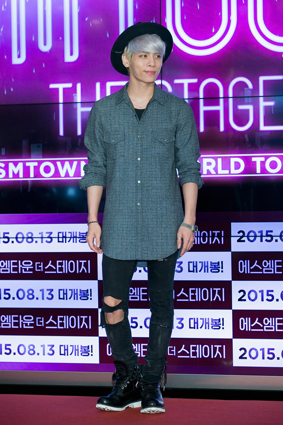 Jonghyun Kim is casually dressed and has a closed-mouth style in front of a lit-up screen.