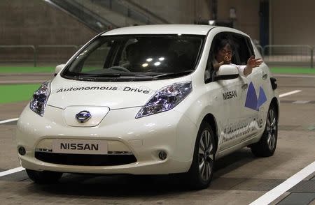 A staff member of Nissan gestures to the media as he rides its LEAF electronic car with the new driving system "Autonomous Drive", which utilizes sensors and cameras to drive automatically, during a photo opportunity at CEATEC (Combined Exhibition of Advanced Technologies) JAPAN 2013 in Chiba, east of Tokyo, October 1, 2013. REUTERS/Yuya Shino