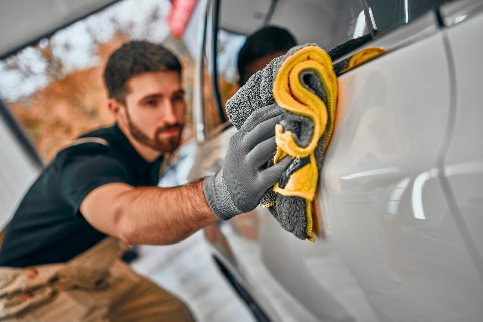 A man wiping down a car's exterior