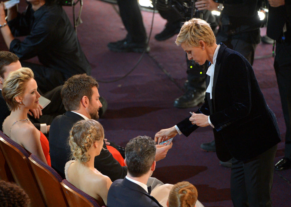 Ellen DeGeneres, right, gives Bradley Cooper a lottery ticket during the Oscars at the Dolby Theatre on Sunday, March 2, 2014, in Los Angeles. (Photo by John Shearer/Invision/AP)