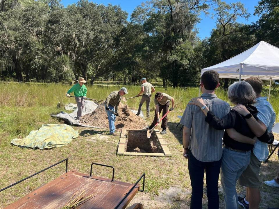 Chris McAliley and her sons, Daniel and Ben Kleiman, look on as volunteers at Prairie Creek Conservation Cemetery bury her mother, Janet McAliley. The volunteer group, which digs all the graves at Prairie Creek, calls itself the Pick and Spade Society.