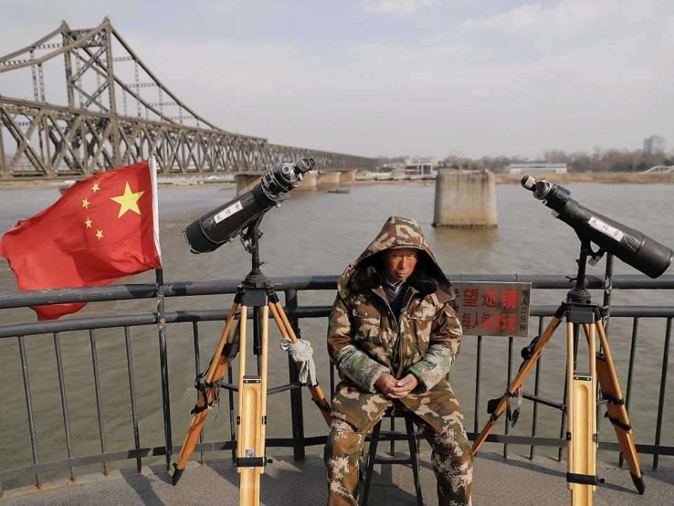 File: A man sits between binoculars he offers to tourists to watch the North Korean side of the Yalu River from the Broken Bridge, bombed by the US forces in the Korean War and now a tourist site, in Dandong, China's Liaoning province. The bridge connects China’s Dandong New Zone to North Korea’s Sinuiju (Reuters)