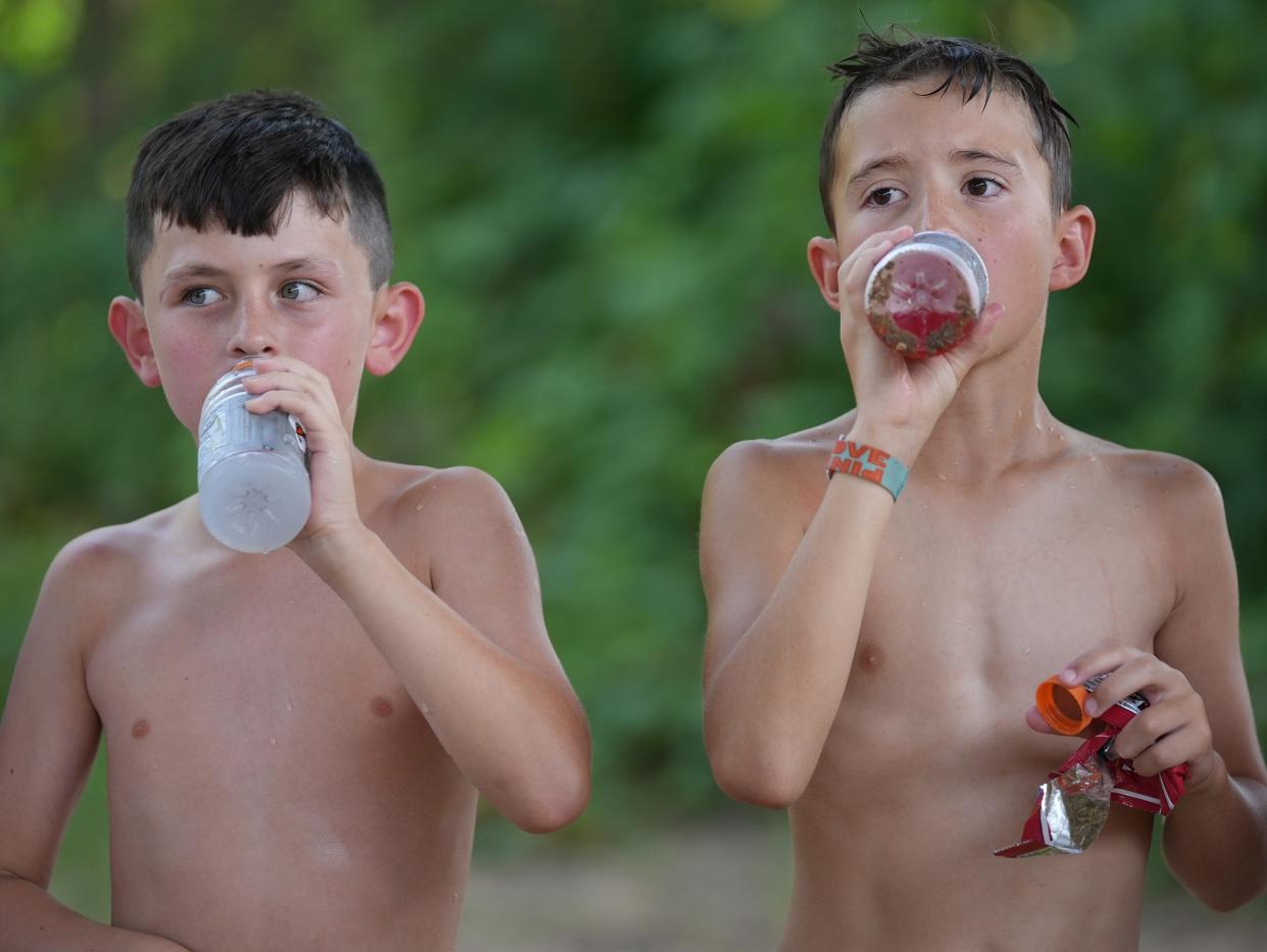 Pennett Bryan, 8, left, and Jack Sheehan, 9, take a hydration break June 12 during Lucas’ Fishing Camp, a day camp for children, at Lady Bird Lake.