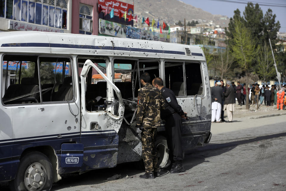 Security personnel inspect a damaged minibus after a bomb explosion in Kabul, Afghanistan, Thursday, March 18, 2021. The bus attack caused numerous deaths and injuries according to police. (AP Photo/Mariam Zuhaib)