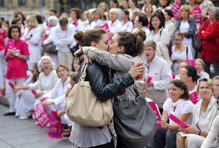 Two women kiss in front of people taking part in a demonstration against gay marriage and adoption by same-sex couples on October 23, 2012 in Marseille, southeastern France. Passions and tensions are rising in France ahead of an expected giant weekend rally against the government's plan to legalise same-sex marriage and adoption that has angered influential Catholic and Muslim groups