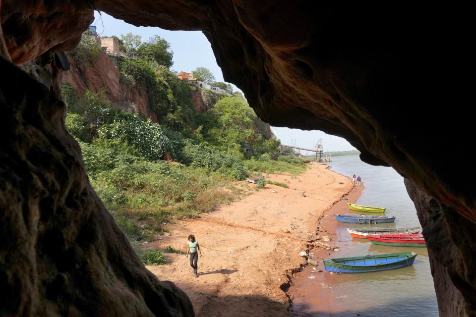 Framed through a cave opening at Ita Pyta Punta or Cape Red Rock, empty boats sit moored on the banks of the Paraguay River, in Asuncion, Paraguay, Wednesday, Sept. 22, 2021, amid a prolonged drought, resulting in low water levels. (AP Photo/Jorge Saenz)