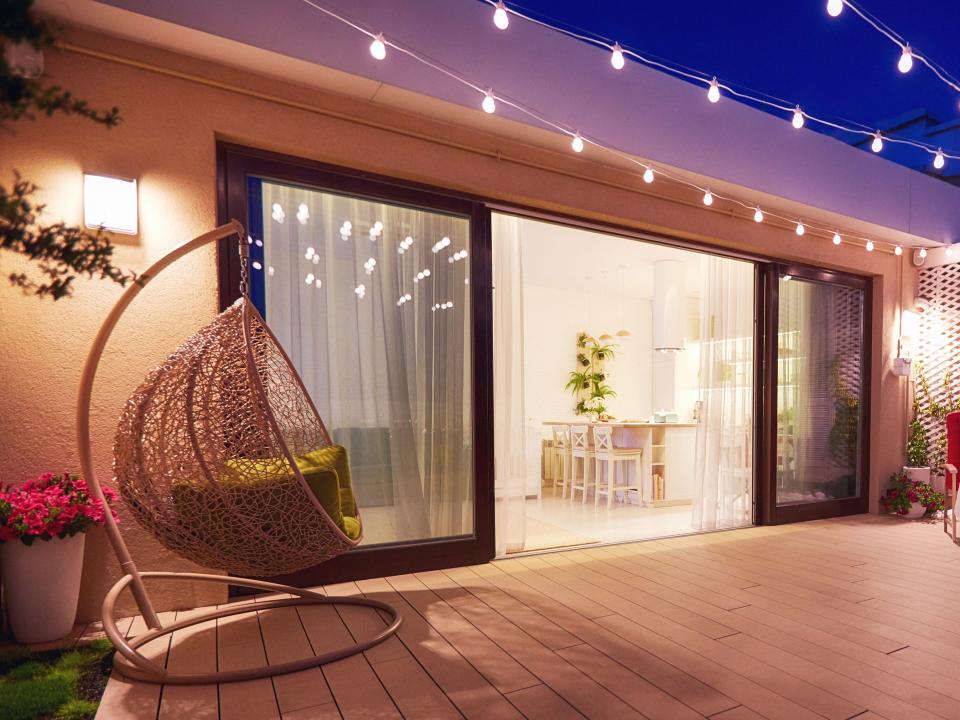 outdoor space at night with string lights and an egg chair in the corner