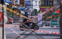 A man rides a scooter past road barricades made from scaffoldings and cordon tapes in Vung Tau, Vietnam, Monday, Sept. 20, 2021. In Vung Tau, just outside Ho Chi Minh city, streets are sealed and checkpoints are set up to control the movement of people. Barbed wire, door panels, steel sheets, chairs and tables are among materials being used to fence up alleys and isolate neighborhoods.(AP Photo/Hau Dinh)