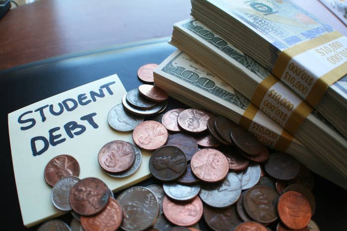 A note with "Student debt" on it next to coins and stacks of $100 bills