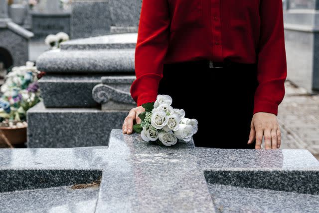<p>Getty</p> A woman placing flowers at a grave (stock image)