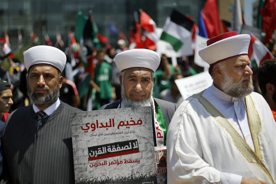 A Palestinians cleric holds a placard with Arabic that reads: "No to the deal of the century. Down with the Bahrain conference" during a demonstration organized by the Islamic militant group Hamas against a US-sponsored Middle East economic workshop in Bahrain, in front of the United Nations headquarters in Beirut, Lebanon, Tuesday, June 25, 2019. The Trump administration is plowing ahead with a $50 billion economic proposal to aid the Palestinians and hopes it'll drive a much-anticipated but unseen Mideast peace plan. A two—day workshop is to begin Tuesday in Bahrain, where the Trump administration's Mideast peace team hopes to drum up regional support and secure financial pledges from Arab and Israeli stakeholders. (AP Photo/Bilal Hussein)