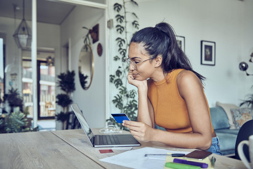 A woman is sitting at a dining table with a laptop and financial statements. Calculates and pays taxes and bills online.