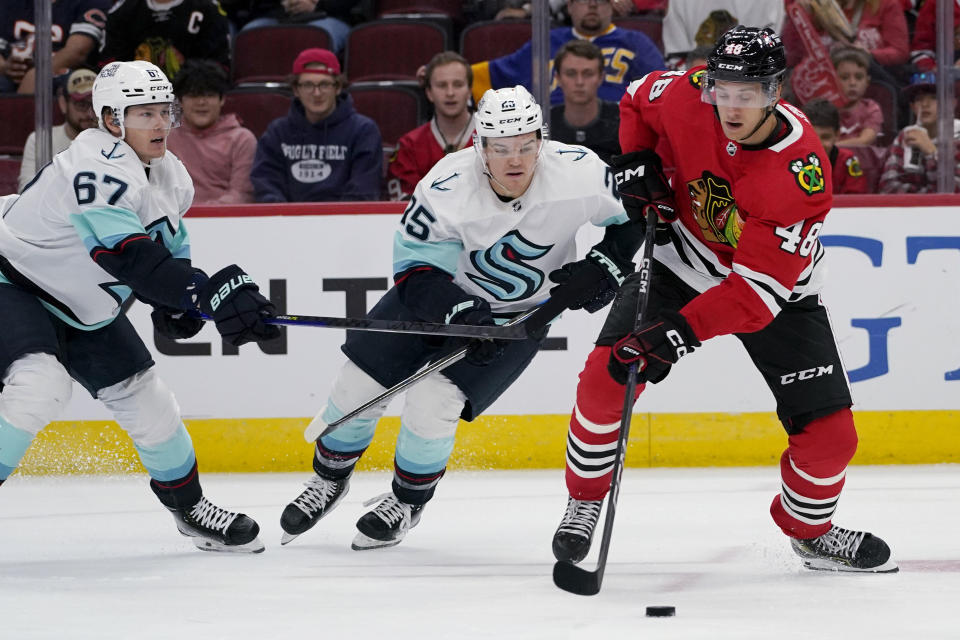 Chicago Blackhawks defenseman Filip Roos, right, controls the puck against Seattle Kraken center Morgan Geekie, left, and center Karson Kuhlman during the first period of an NHL hockey game in Chicago, Sunday, Oct. 23, 2022. (AP Photo/Nam Y. Huh)