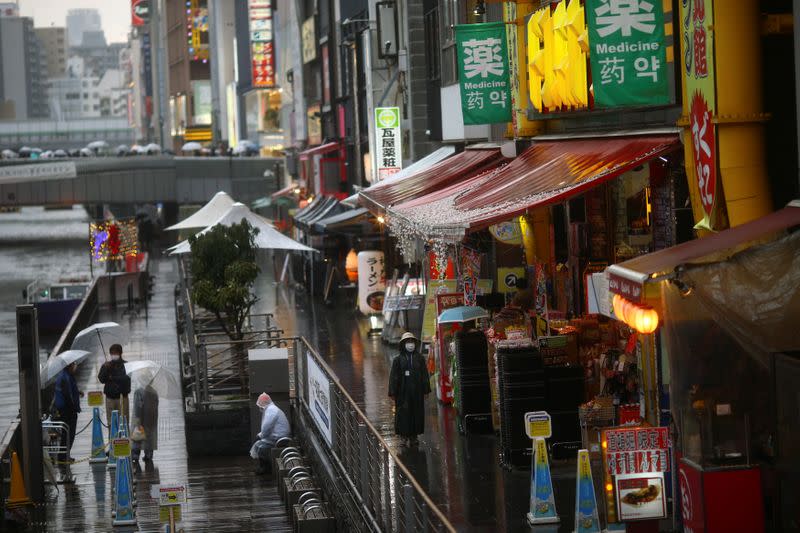 A woman, wearing protective mask following an outbreak of the coronavirus disease (COVID-19), walks on an almost empty street in the Dotonbori entertainment district of Osaka