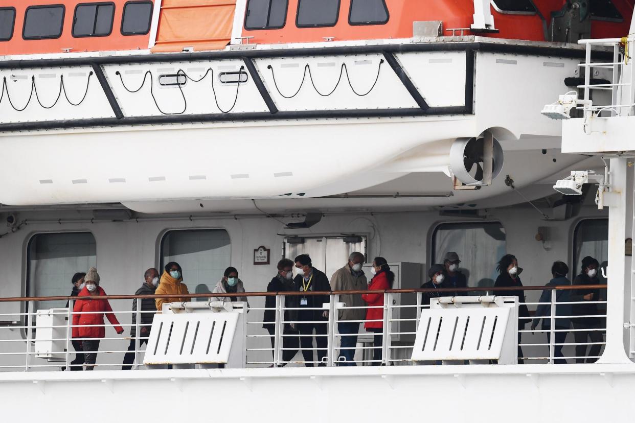 Passengers walk along the deck of the Diamond Princess cruise ship in February 2020. Around 3,600 people were quarantined onboard due to fears of a coronavirus outbreak: (Photo by CHARLY TRIBALLEAU/AFP via Getty Images)