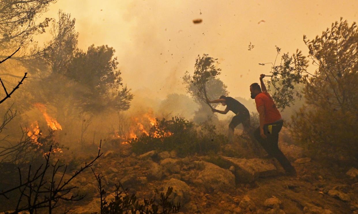 <span>Residents help firefighters try to extinguish a wildfire burning near Athens, on 19 July 2023.</span><span>Photograph: Miloš Bičanski/Getty Images</span>