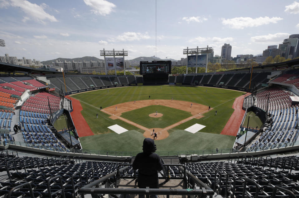 A TV cameraman films in the empty stadium as a part of precaution against the new coronavirus during the pre-season baseball game between Doosan Bears and LG Twins in Seoul, South Korea, Tuesday, April 21, 2020. South Korea's professional baseball league has decided to begin its new season on May 5, initially without fans, following a postponement over the coronavirus. (AP Photo/Lee Jin-man)