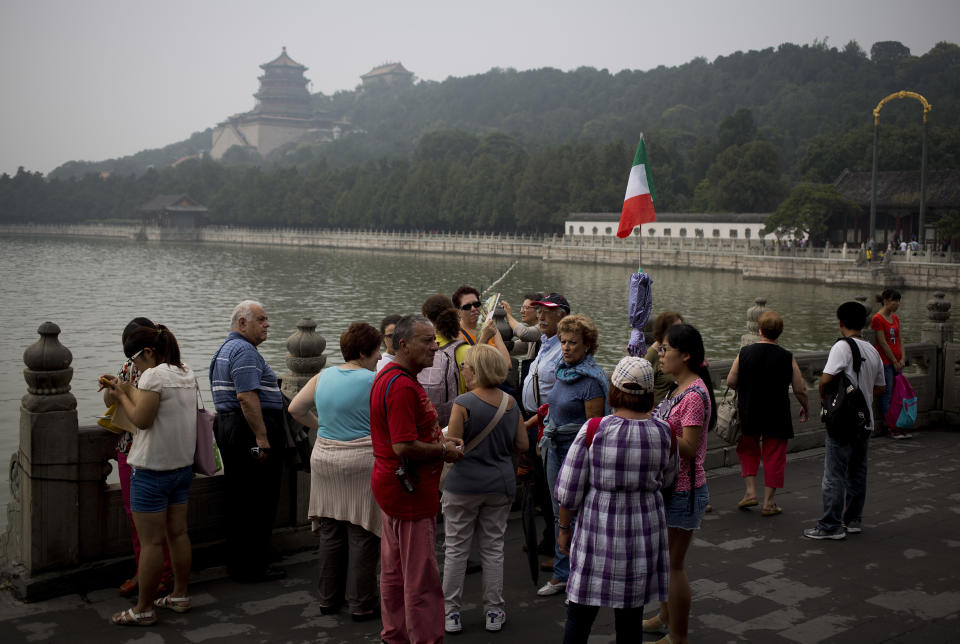 In this Wednesday, Aug. 28, 2013 photo, a group of Italian tourists visit the Summer Palace with the Buddhist towers in the background in Beijing. China’s tourism industry has grown at a fast pace since the country began free market-style economic reforms three decades ago. However, it's latest tourism slogan "Beautiful China" has been derided as particularly inept at a time when record-busting smog has drawn attention to the environmental and health costs of China’s unfettered industrialization. Some point to unsophisticated marketing as an explanation. (AP Photo/Andy Wong)