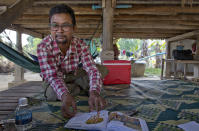 Vannak Anan Prum, who was double trafficked, points to his illustration of an abusive former boss, a palm oil estate owner, in his graphic novel depicting his life as a slave on a fishing boat before being sold onto a Malaysian palm oil plantation, at his home in Pursat, Cambodia, Saturday, March 30, 2019. (AP Photo/Gemunu Amarasinghe)