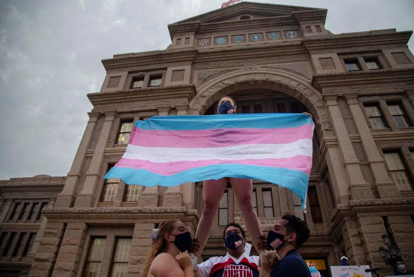 Ali Cross of the Austin Cheer squad waved a trans flag in April while her teammates held her up on the steps of the state Capitol at a rally against anti-trans legislation.