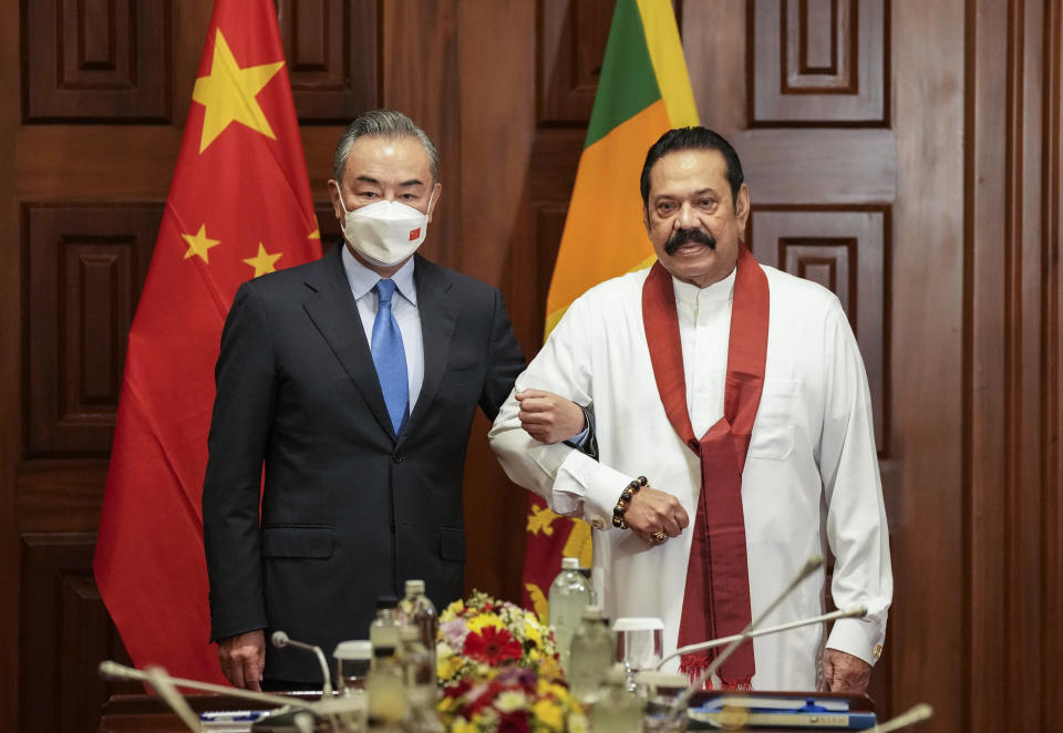 Chinese Foreign Minister Wang Yi, left, poses for media before his meeting with Sri Lankan Prime Minister Mahinda Rajapaksa in Colombo, Sri Lanka, Sunday, Jan. 9, 2022. (AP Photo/Eranga Jayawardena)