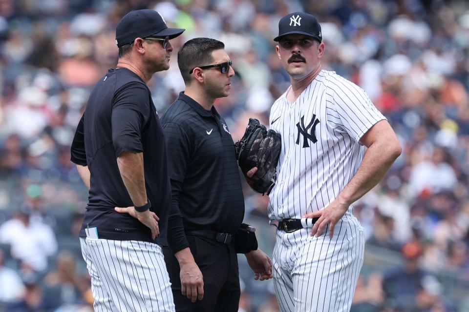 Yankees starting pitcher Carlos Rodon (55) talks with medical staff and manager Aaron Boone (17) after an injury during the third inning against the Houston Astros at Yankee Stadium on Aug. 6, 2023.