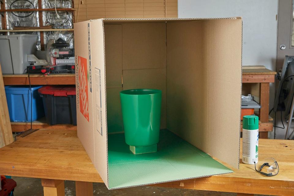 Green painted plastic bin in a cardboard box.