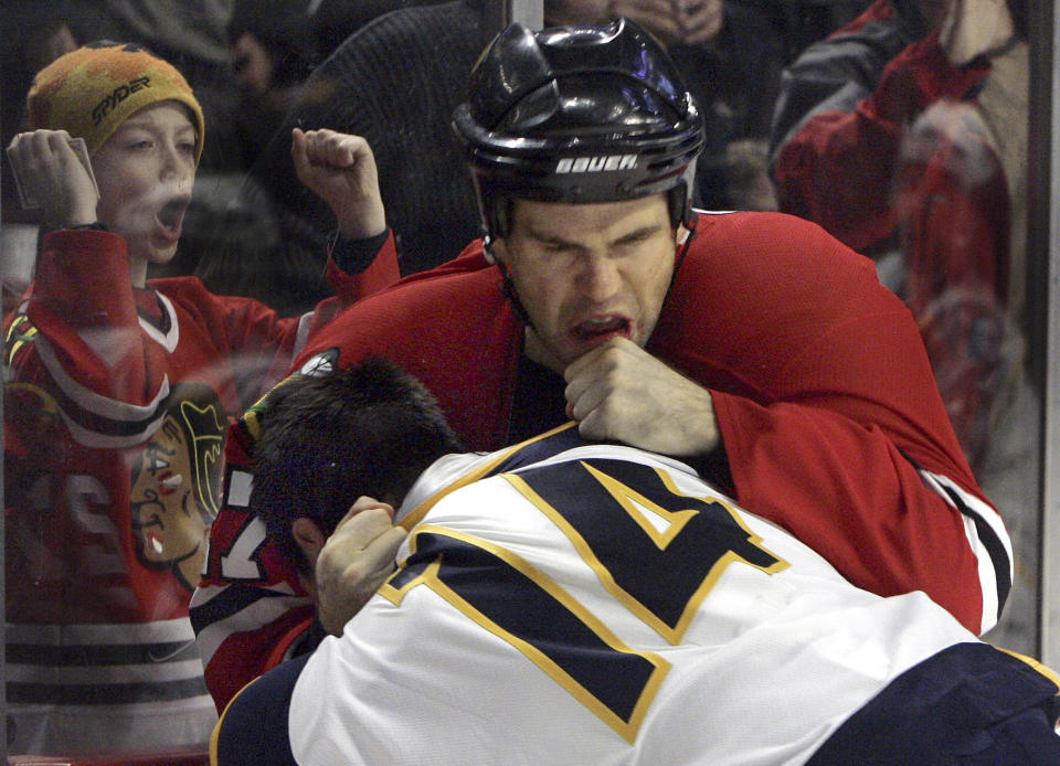 FILE - Chicago Blackhawks' Todd Simpson, rear, fights with Nashville Predators' Jordin Tootoo (14) as a fan cheers them on during the third period of an NHL hockey game Wednesday, Dec. 21, 2005, in Chicago. The Predators won 6-1. Twenty years since the Philadelphia Flyers and Ottawa Senators broke the NHL record for penalty minutes with their brawl-filled game, fighting has evolved in hockey to the point of being rare but not gone.(AP Photo/Jeff Roberson, File)