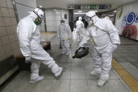 Workers wearing protective gears help clean each other's suits after disinfecting as a precaution against the coronavirus at a subway station in Seoul, South Korea, Friday, Feb. 21, 2020. South Korea on Friday declared a "special management zone" around a southeastern city where a surging viral outbreak, largely linked to a church in Daegu, threatens to overwhelm the region's health system. (AP Photo/Ahn Young-joon)