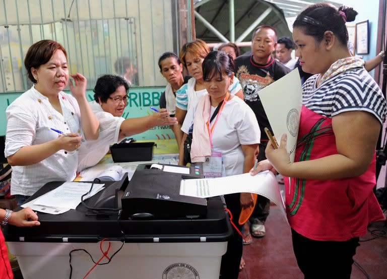 A woman (R) scans a ballot on an electronic vote-counter at a polling station during mid-term elections in Manila, on May 13, 3013. People are going to the polls to choose thousands of local leaders plus national legislators in what is seen as a referendum on the presidency of reformist Benigno Aquino