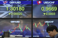 A currency trader talks near the screens showing the foreign exchange rates at the foreign exchange dealing room in Seoul, South Korea, Wednesday, Jan. 15, 2020. Asian shares have retreated as conflicting reports raised concerns over the likely outcome of a trade deal to be signed by the U.S. and China. (AP Photo/Lee Jin-man)