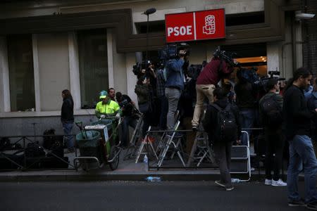 A municipal cleaner works next to the media as they stand outside the headquarters of Spain's Socialist party (PSOE) while waiting for the start of the party's assembly meeting in Madrid, Spain, October 1, 2016. REUTERS/Susana Vera