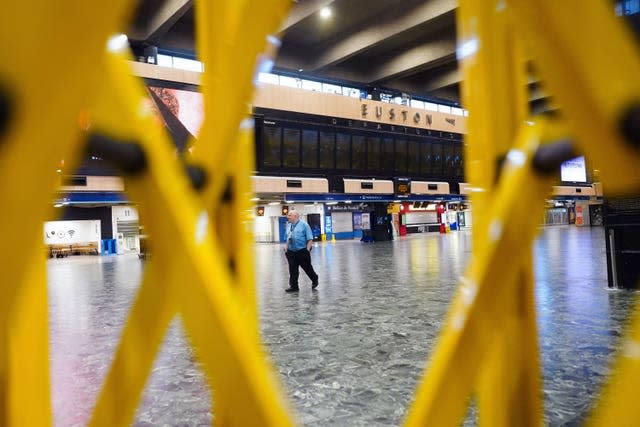 A person walking past the empty departures board at Euston station in London