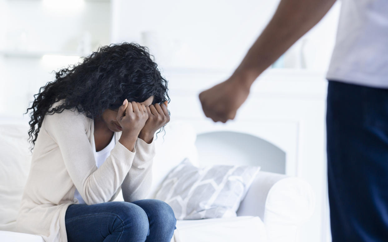 Domestic abuse. Young woman suffering from home violence, hiding her face from husband's fist.