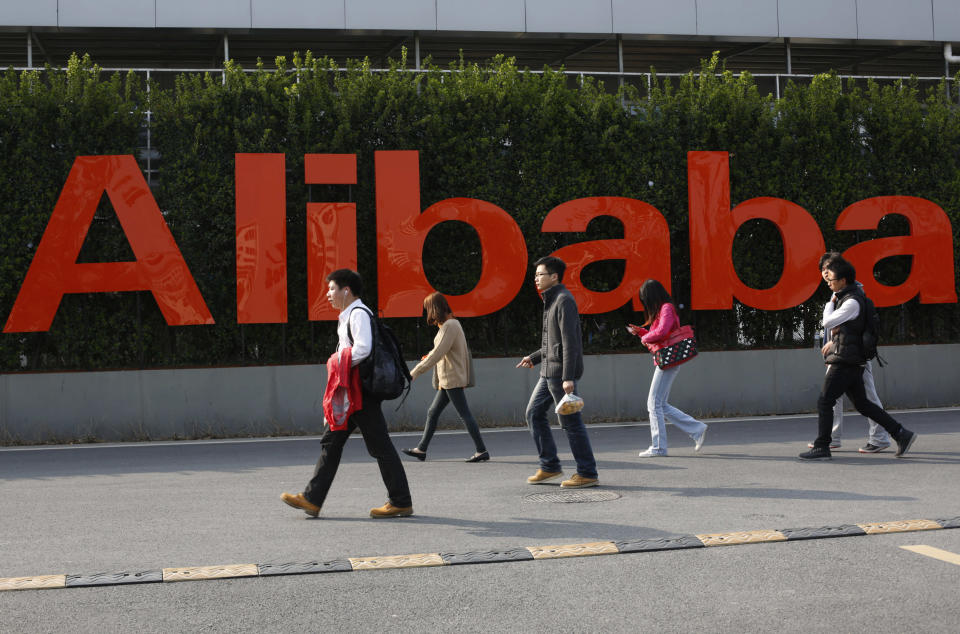 In this March 17, 2014 photo, people walk past a company logo at the headquarters of Alibaba Group in Hangzhou, in eastern China's Zhejiang province. Even before Alibaba went online, its founder talked about making the fledgling e-commerce company a global player. (AP Photo) CHINA OUT