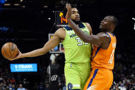 Minnesota Timberwolves center Karl-Anthony Towns (32) looks to pass as Phoenix Suns center Bismack Biyombo (18) defends during the first half of an NBA basketball game, Friday, Jan. 28, 2022, in Phoenix. (AP Photo/Matt York)