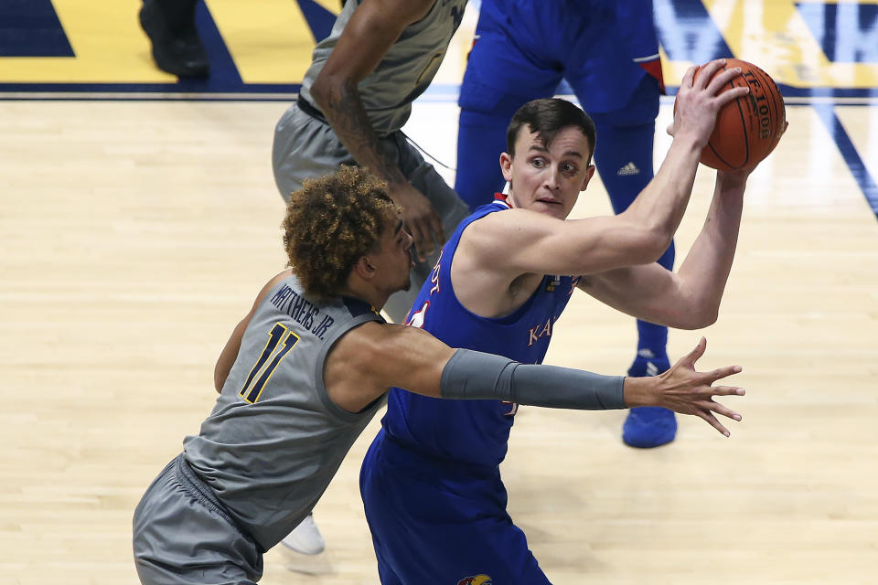 Kansas guard Latrell Jossell (4) passes while defended by West Virginia forward Emmitt Matthews Jr. (11) during the second half of an NCAA college basketball game Saturday, Feb. 6, 2021, in Morgantown, W.Va. (AP Photo/Kathleen Batten)