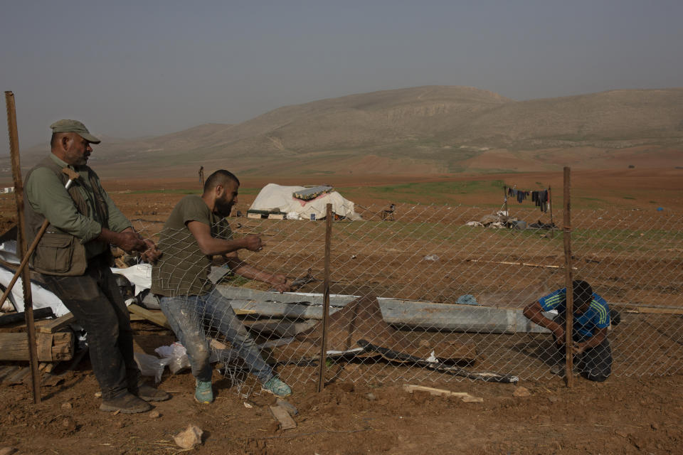 Palestinian Bedouins boy rebuild a fence for an animal pen after Israeli troops demolished tents and other structures of the Khirbet Humsu hamlet in the Jordan Valley in the West Bank, Wednesday, Feb. 3, 2021. A battle of wills is underway in the occupied West Bank, where Israel has demolished the herding community of Khirbet Humsu three times in as many months, displacing dozens of Palestinians. Each time they have returned and tried to rebuild, saying they have nowhere else to go. (AP Photo/Maya Alleruzzo)