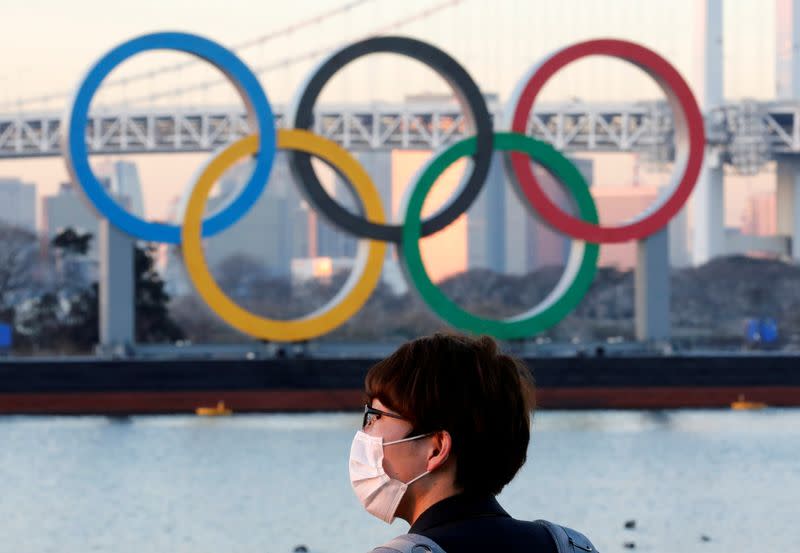 FILE PHOTO: A man wears a protective mask amid the coronavirus disease (COVID-19) outbreak, in front of giant Olympic rings in Tokyo