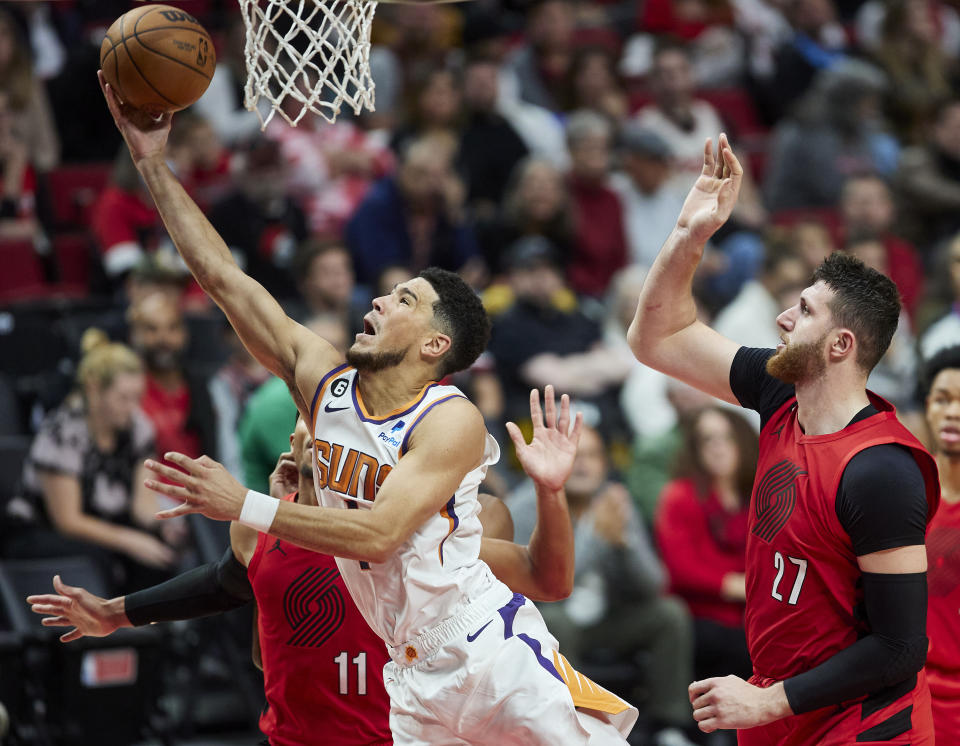 Phoenix Suns guard Devin Booker, left, shoots in front of Portland Trail Blazers center Jusuf Nurkic, right, during the second half of an NBA basketball game in Portland, Ore., Friday, Oct. 21, 2022. (AP Photo/Craig Mitchelldyer)